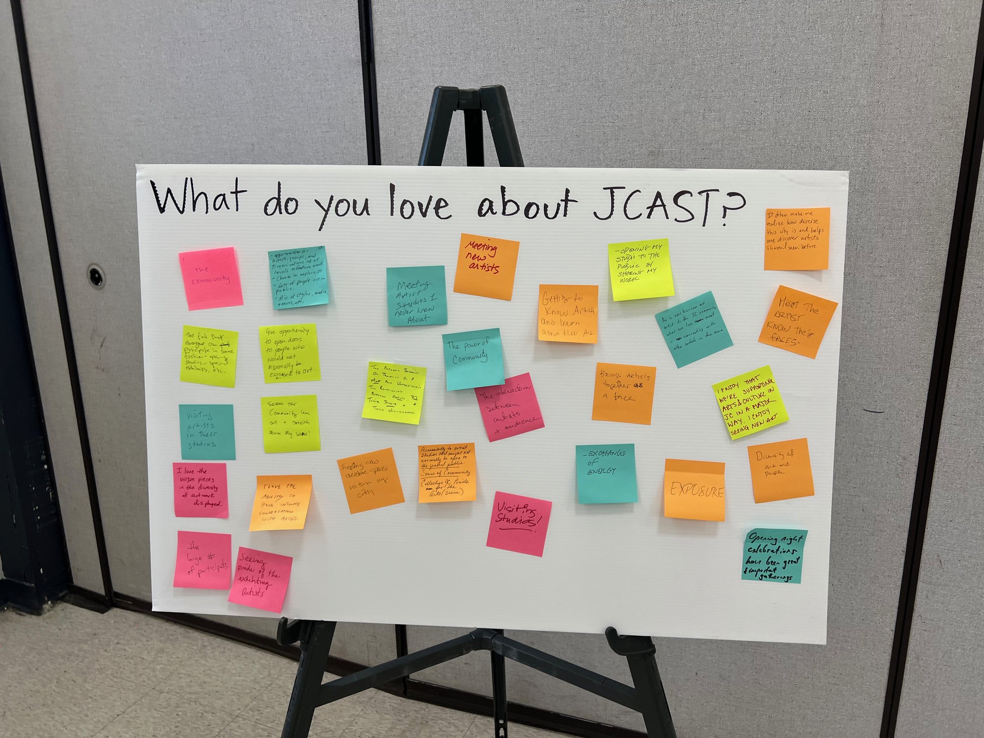 Easel board reading 'What do you love about JCAST?' covered in handwritten sticky notes.