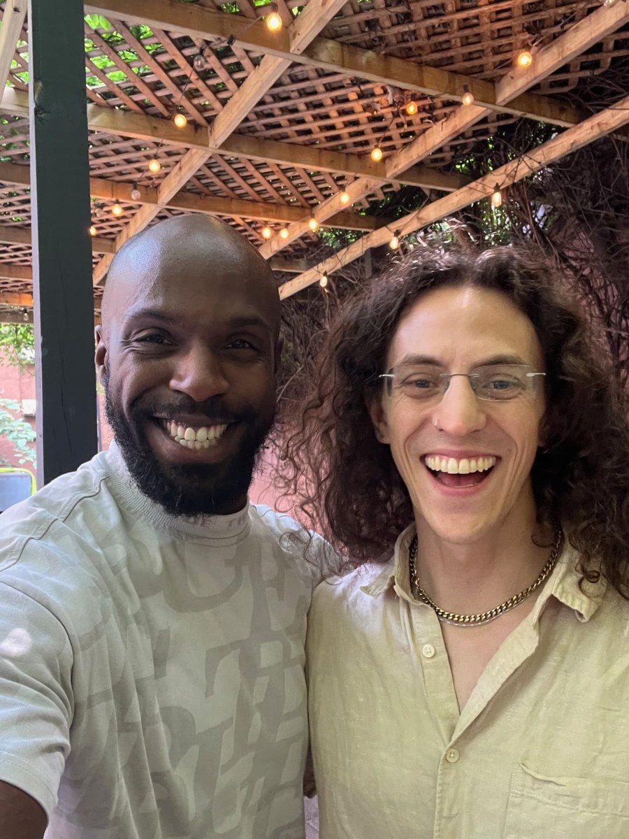 Elisha Dorsey and Councilman Jake Efros standing together outdoors under a wooden pergola strung with lights.